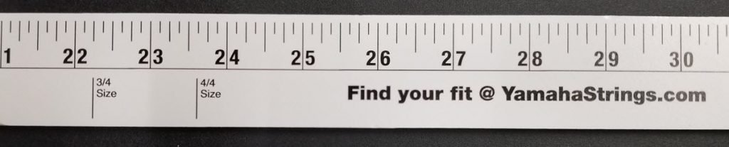 Find your fit stick Closeup of measuring tape with not only the usual inches and portion of an inch marked, but also marks for 3/4 size and 4/4 size as it pertains to violins. The words "Find Your Fit @ YamahaStrings.com" is also displayed on the tape.