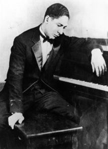 Jelly-Roll-Morton-gettyimages-2635587watermark Man in tuxedo sitting at a piano.
