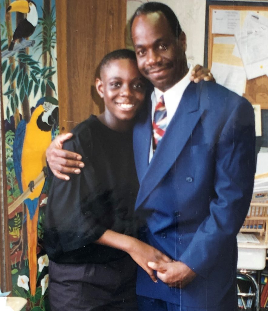 Man in suit and tie hugging his son as they both smile for the camera.